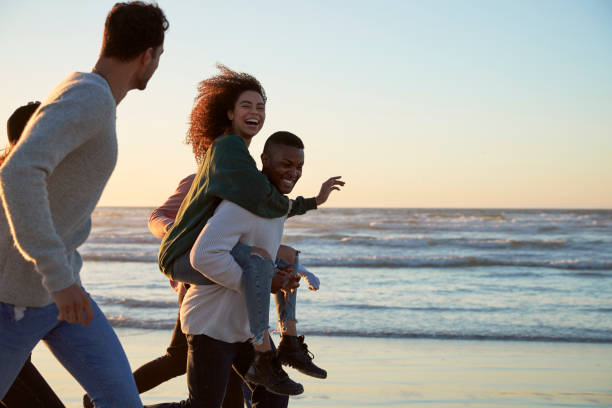 istock Group Of Friends Having Fun Running Along Winter Beach Together 928407722