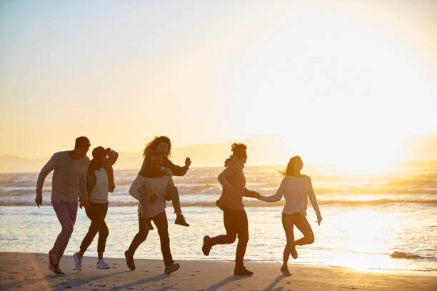 istock Silhouette Of Friends Having Fun Running Along Winter Beach 928407736