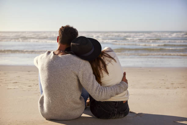 Romantic Couple Sitting On Winter Beach Together Stock Photo - Download  Image Now - Couple - Relationship, Rear View, Sea - iStock
