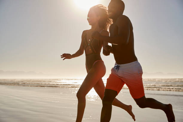 istock Couple Having Fun Running Through Waves On Beach Vacation 928410692