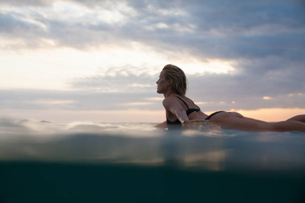 istock sportswoman lying on surf board in ocean 928411112