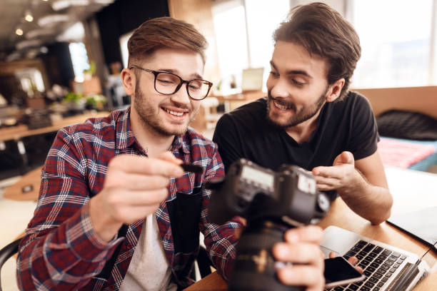 istock Two freelancer men taking out memory card at laptop at desk. 928411388