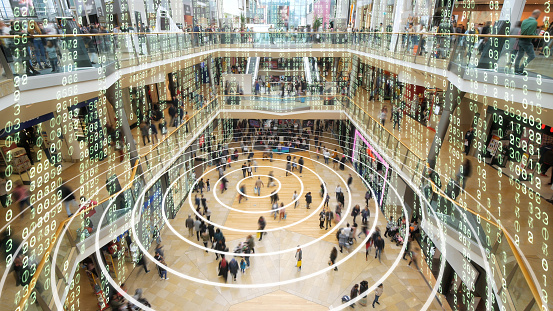 Radio waves spreading out from a mobile phone in a shopping mall with matrix style data layered on top.