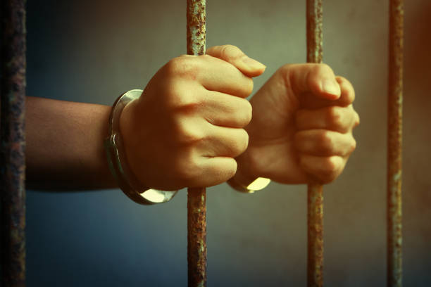 istock hand of prisoner holding metal prison 928418176