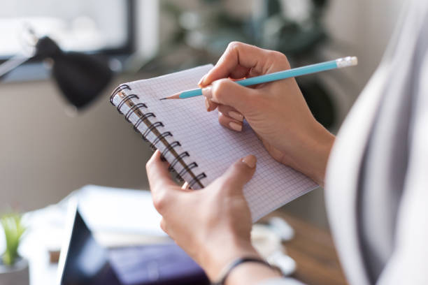 istock cropped image of businesswoman writing something in notebook 928427404