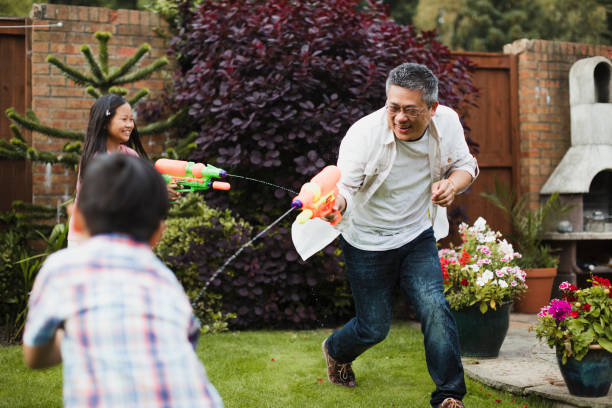 familia que tiene una pelea de agua - pistola de agua fotografías e imágenes de stock