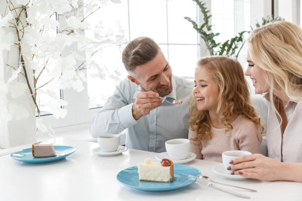 istock father feeding his daughter with cake while they spending time in cafe together 928433540