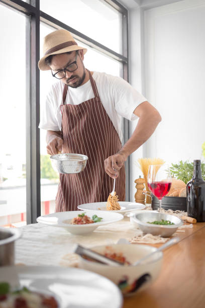 istock Handsome bearded cheef cook prepairing spaghetti on a kitchen, Chef cooks meal 928437024
