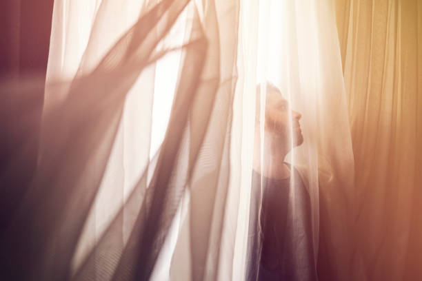 istock Man opening window curtain in bedroom 928438378