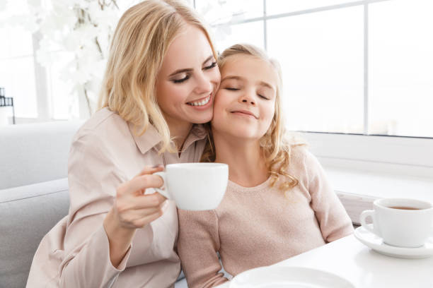 istock mother and daughter cuddling while drinking tea in cafe 928438502