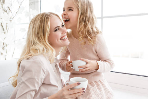 istock mother and daughter drinking tea and laughing together 928438644