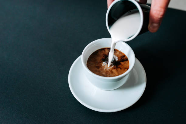 gießen die milch in schwarzen kaffee. isolierte hintergrund. - black coffee fotos stock-fotos und bilder