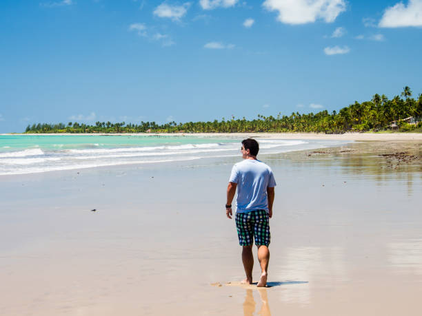 istock man walking along beach view on a summer day 928448154
