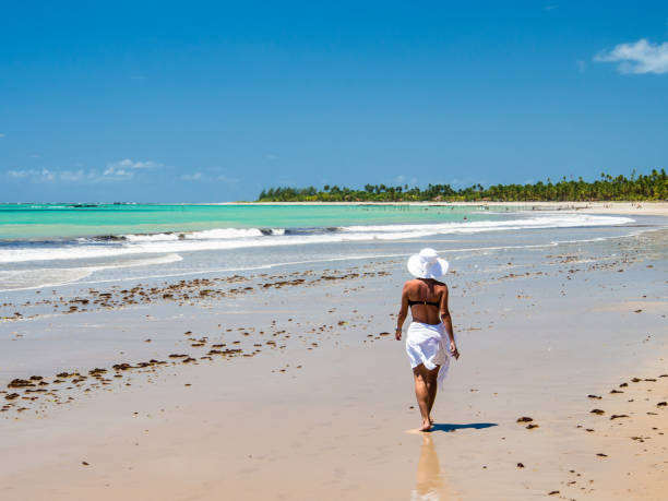 istock attractive woman walking along beach with view on a summer day 928448732