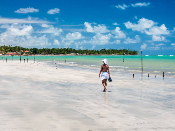 istock attractive woman walking along beach with view on a summer day 928448916