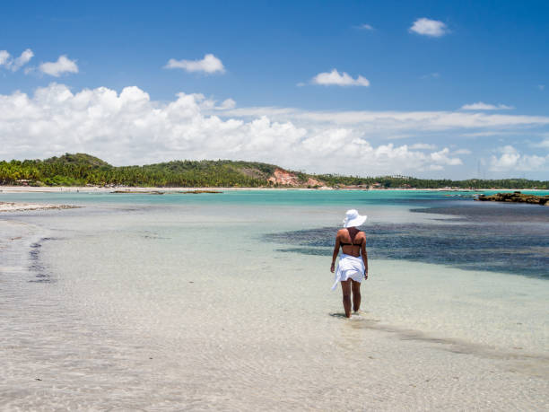istock attractive woman walking along beach with view on a summer day 928448936