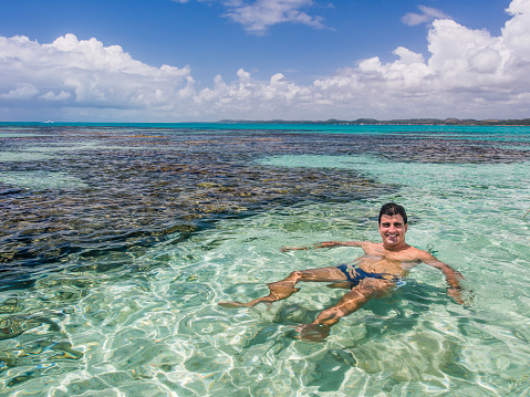 man relaxing in crystal clear water on sunny day, Maragogi, Alagoas, Brazil