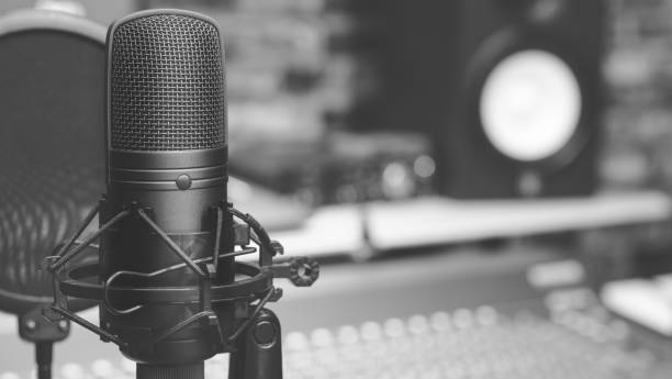 istock condenser microphone on audio mixing board & studio monitor speakers background 928456840