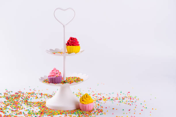 White two tier serving tray and miniature multicolored sugar cupcakes with sprinkles