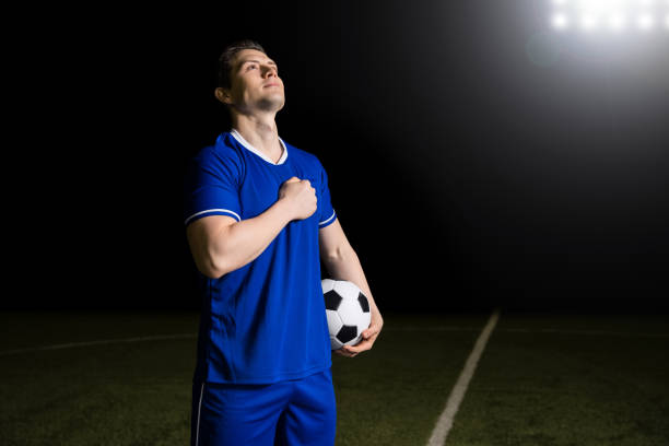 Proud footballer listening to national anthem Young soccer player in blue jersey feeling proud of his country while listening to his national anthem in a world cup national anthem stock pictures, royalty-free photos & images