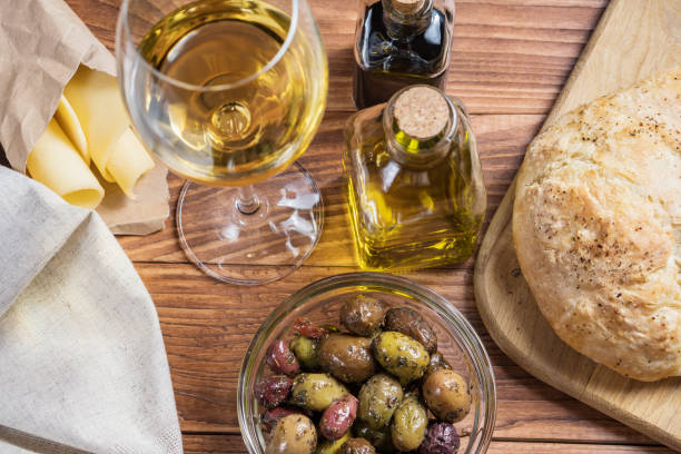 bowl with different kind of olives, glass of wine, cheese and  fresh bread ciabatta on the wooden table. - fruit freshness tree foods and drinks imagens e fotografias de stock