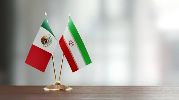 istock Mexican And Iranian Flag Pair On A Desk Over Defocused Background 928474276
