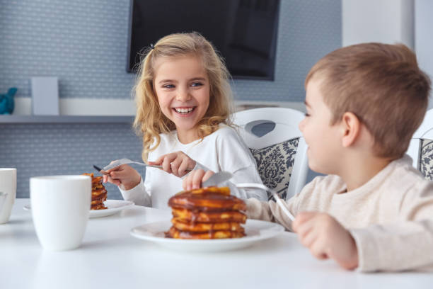 istock happy little kids having breakfast together 928474648