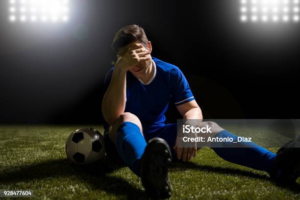 Photo libre de droit de Footballeur Déçue Assis Sur Le Terrain Avec Gazon banque d'images et plus d'images libres de droit de Football - Football, Défaite, Ballon de football