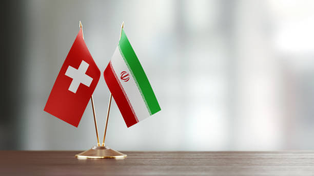 istock Swiss And Iranian Flag Pair On A Desk Over Defocused Background 928477898