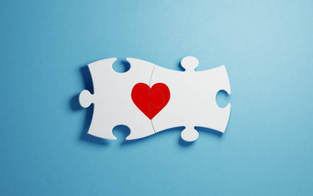 White puzzles forming a heart shape on blue background. Horizontal composition with copy space. Great use for find love concepts.