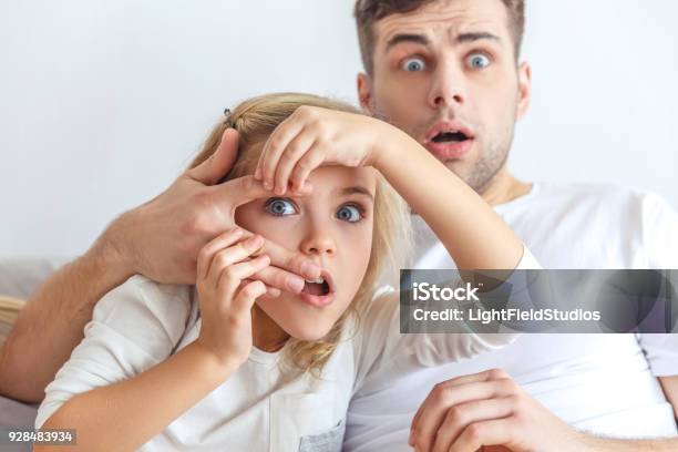 Shocked Father And Daughter Watching Scarry Movie Together Stock Photo - Download Image Now