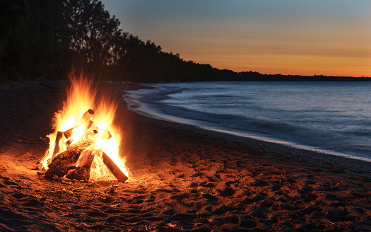 Glowing bonfire on the beach at sunset