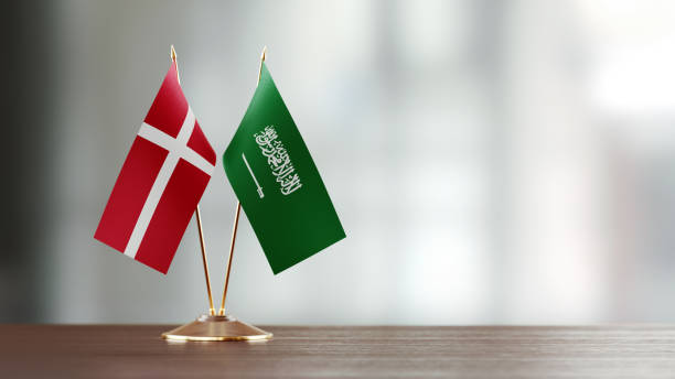 istock Danish And Saudi Arabian Flag Pair On A Desk Over Defocused Background 928499812