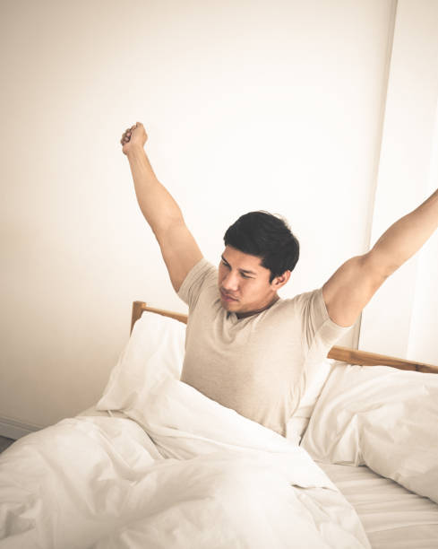 istock Asian male is stretching out after woke up on bed 928516032