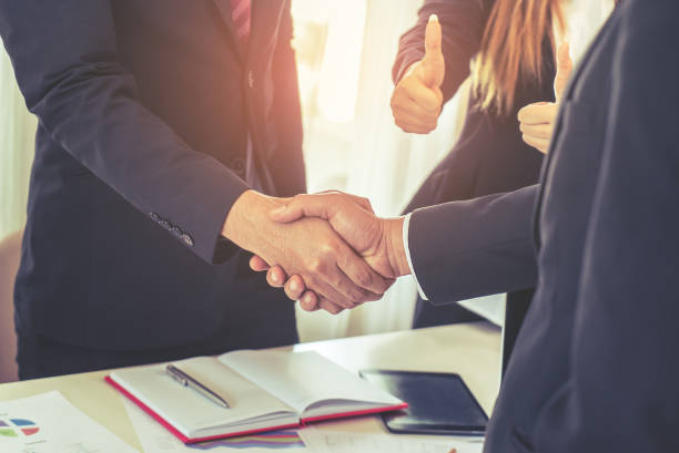istock business man with low handshake with partner and woman cheering 928517350