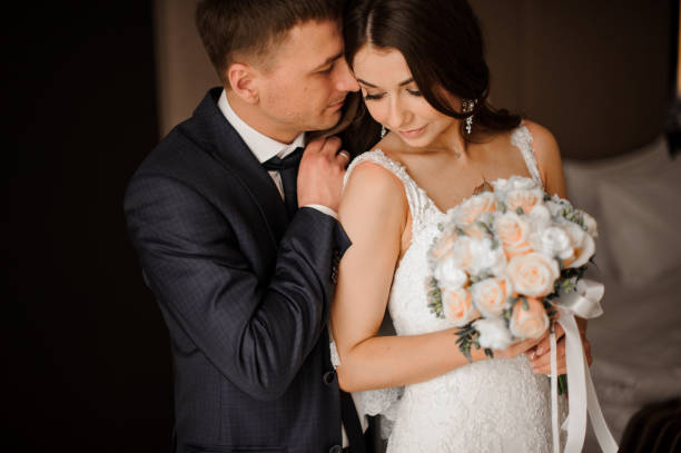 istock young bridegroom gently hugs his charming bride with a bouquet 928524044
