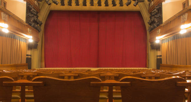 istock Theatre stage with closed curtain and empty wood seats 928538202