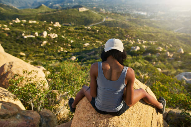 istock female african american hiker looking down while sitting on large boulder 928549514