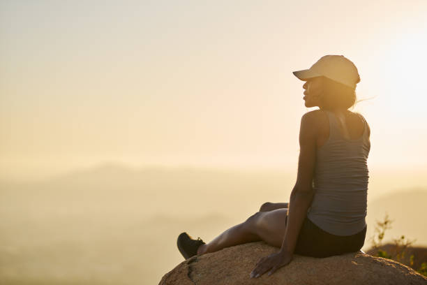 fit hiker resting on rock on top of mountain watching sunset