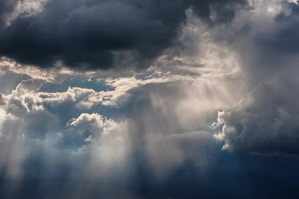 istock rain and sunrays on a blue sky. Stormy dark clouds 928559700