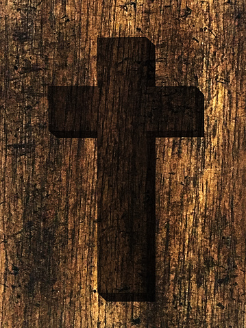 A darkened Christian cross symbol on a vertical rustic natural brown wood grain background. This Salvation symbol represents the death and resurrection of Jesus Christ and is a special celebration event especially at the Holy Week, Easter, Passover, Good Friday, and Christmas.