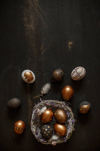 istock Golden decorated easter eggs against black wooden background 928565952