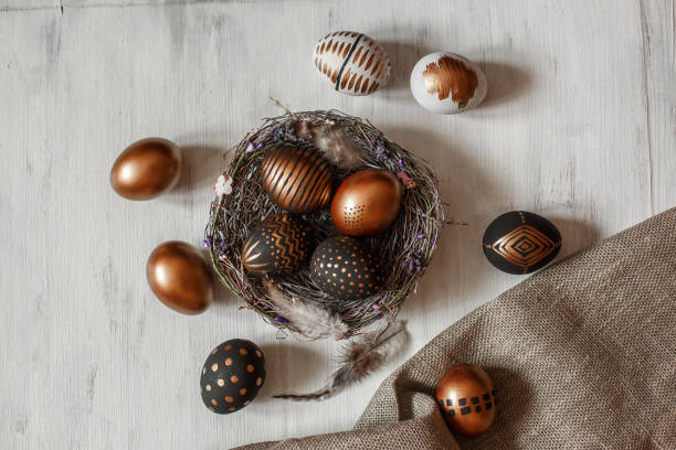 istock Golden decorated easter eggs against white wooden background 928566328
