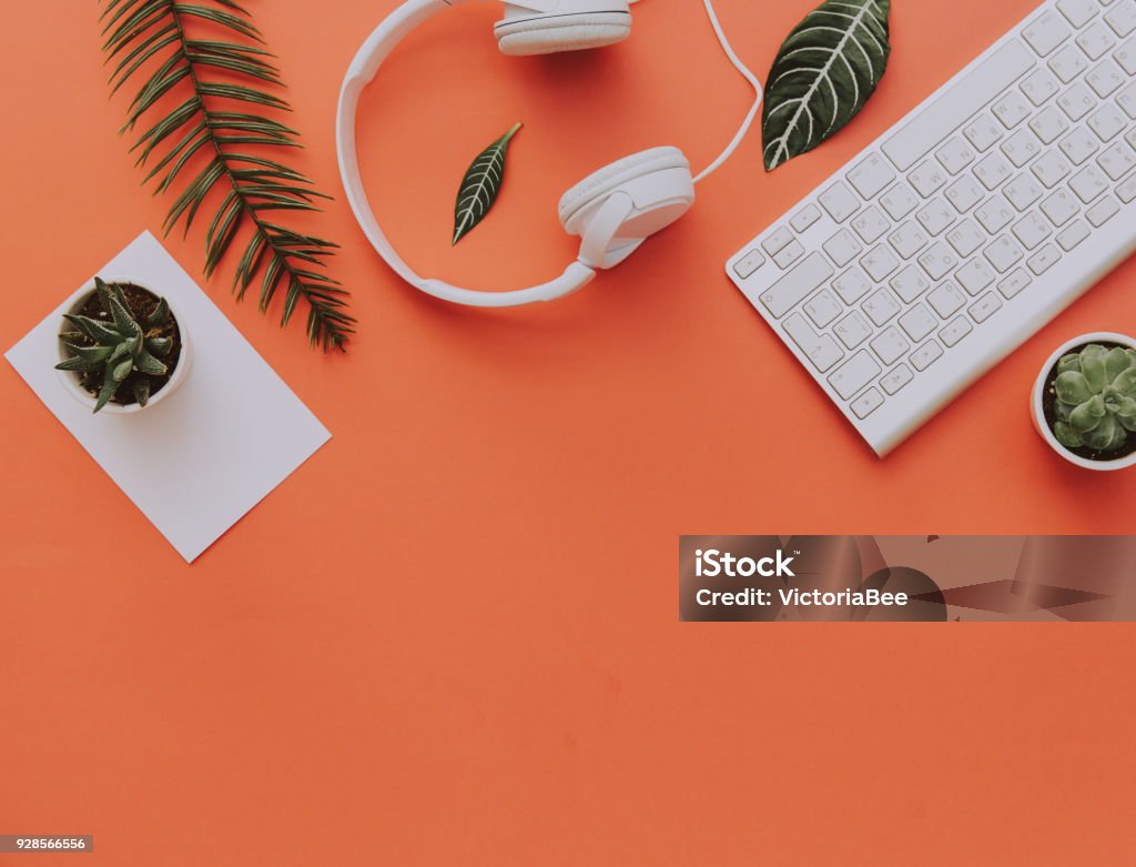 Kreative Wohnung lag der Arbeitsbereich Schreibtisch, Büromaterial, Tastatur, Kopfhörer und Lifestyle-Objekten auf orangem Hintergrund mit Textfreiraum - Lizenzfrei Schreibtisch Stock-Foto