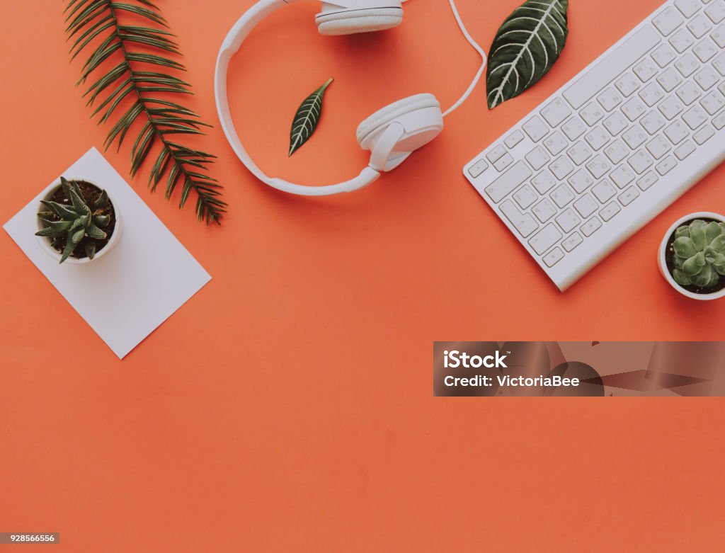 Creative flat lay of workspace desk, office stationery, keyboard, headphones and lifestyle objects on orange background with copy space Desk Stock Photo