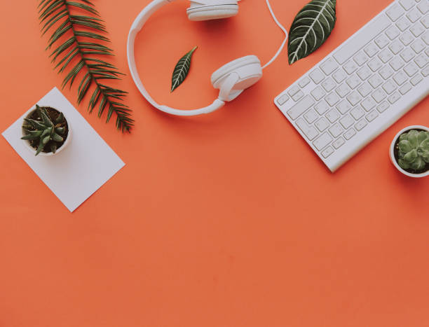 Creative flat lay of workspace desk, office stationery, keyboard, headphones and lifestyle objects on orange background with copy space stock photo