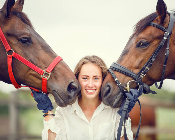 Young rider girl having fun with two her horses. Equestrian sport concept background