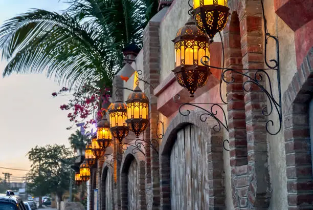 View of building facade and street lights in Cabo San Lucas, Mexico, at dusk.