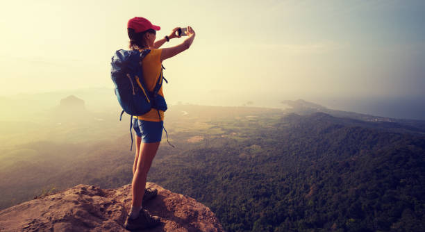 istock Successful female hiker taking photo stand on cliff edge 928630440