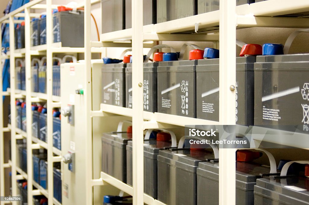 UPS batteries on rows of shelves Strings of batteries for the Uninterruptable Power Supply (UPS) for a datacenter.  A transfer switch is situated between the two battery banks. Battery Stock Photo